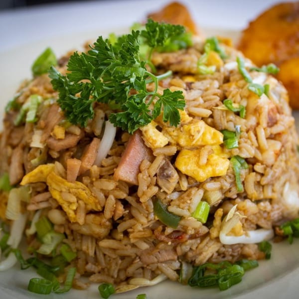Close-up of fried rice with egg, ham, and green onions, garnished with parsley.