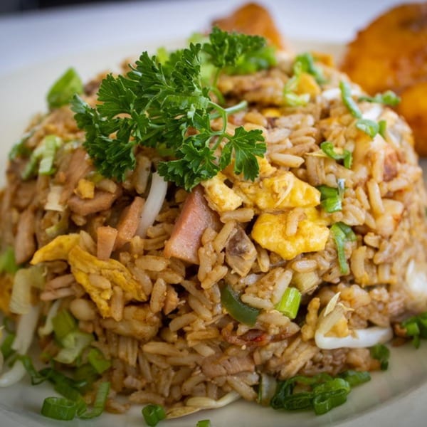 Close-up of fried rice with egg, ham, and green onions, garnished with parsley.